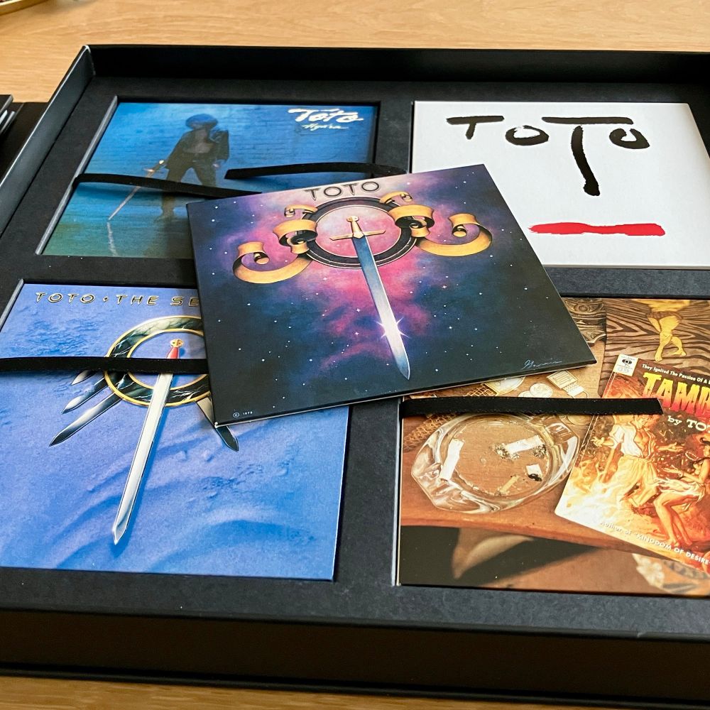 The CD cassette of the TOTO All In boxset openened on my salon table with the TOTO album mini-LP sleeve on top.