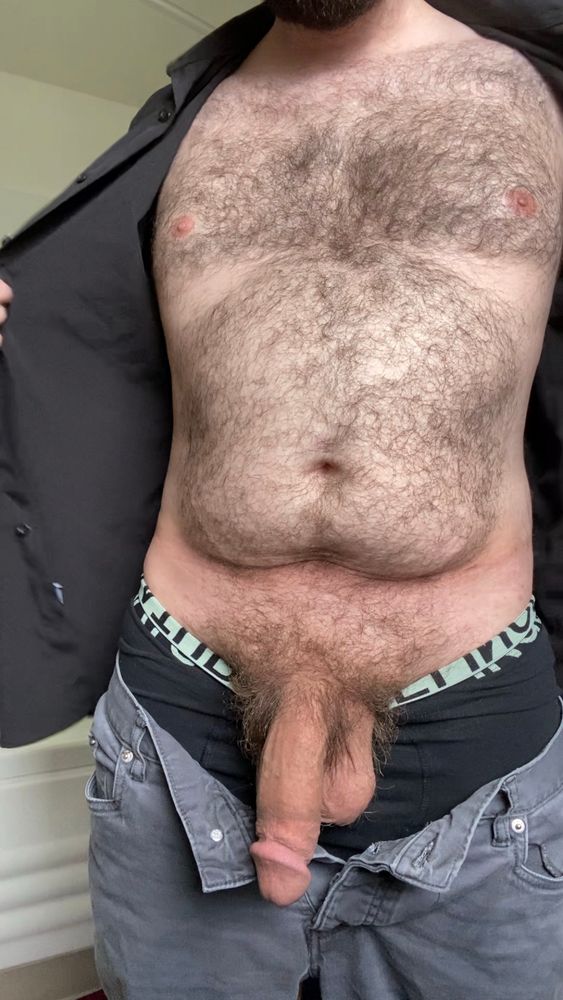 Me standing with an unbuttoned black long sleeve shirt, held open to show my hairy chest and stomach. My gray pants unbuttoned, with my huge bushy soft cock and heavy balls pulled out for display