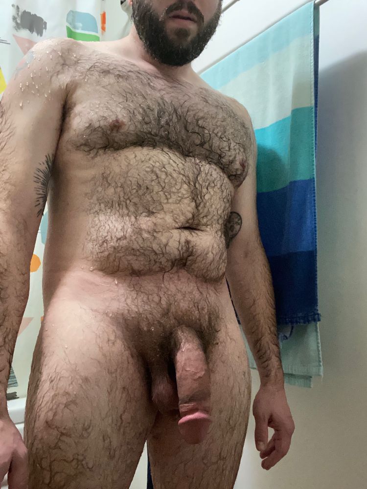 Hairy, bearded, tattooed me standing nude in the bathroom, soaking wet from a shower and with a huge semi hard cock. 