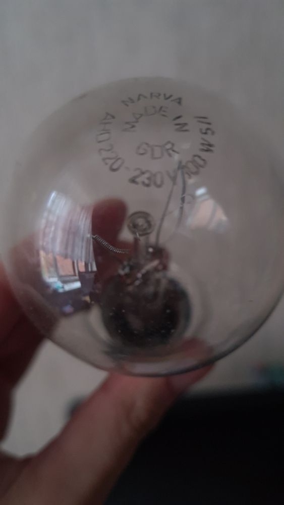 A photo of hand holding a burnt out light bulb with the brand "Narva" and "Made in GDR" printed on it. 