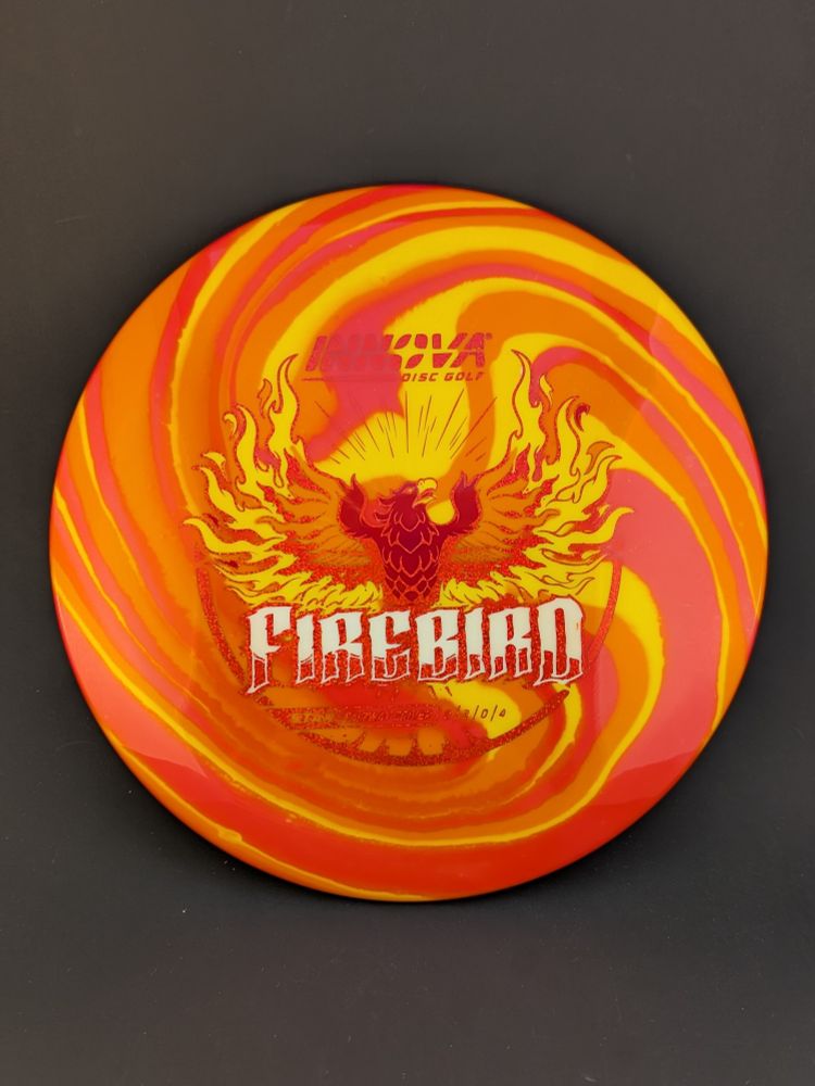 An Innova star firebird disc golf driver dyed with a red, orange, and yellow pattern