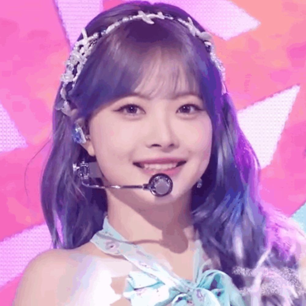 a girl with blue hair is wearing a headband and a microphone while smiling .