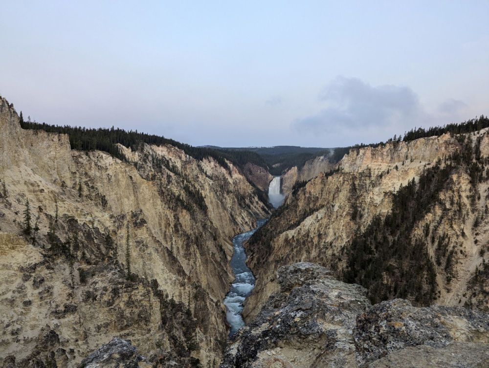 Photo of a landscape with a canyon with a waterfall and river running through it stretching for several miles.