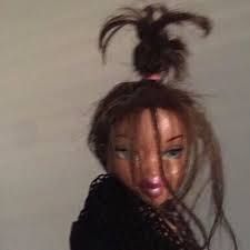 blurry picture of a bratz doll with her hair tied up in an extremely messy bun, her face obscured by long strands of hair and she looks like shes wrapped in a black cardigan