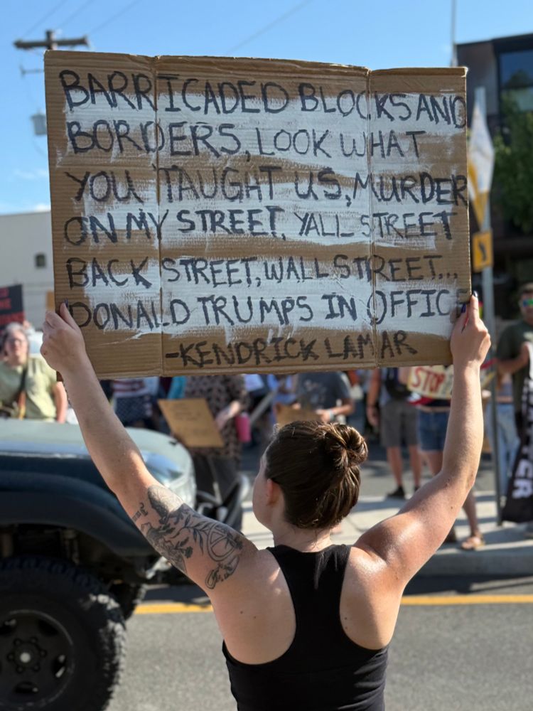 Sign that says “barricaded blocks and borders, look what you taught us, murder on my street, yall street, back street, Wall Street…Donald Trump in office. -Kendrick Lamar”