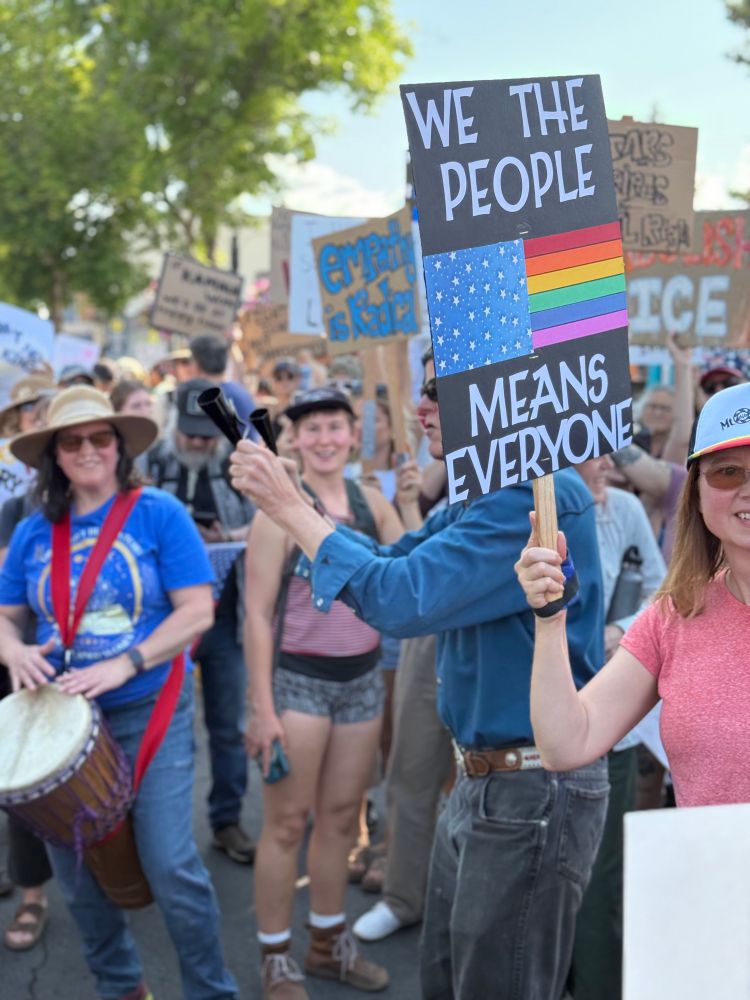 Sign that says “we the people means everyone” with a pride flag on it.