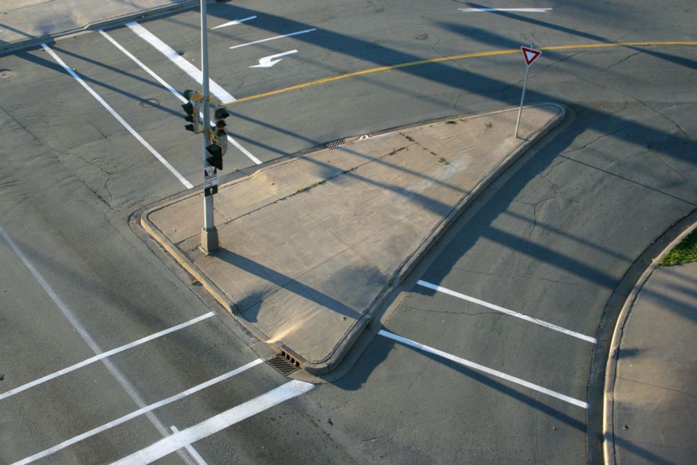 A triangular traffic island photographed from
above, with slanting shadows created by early morning light.