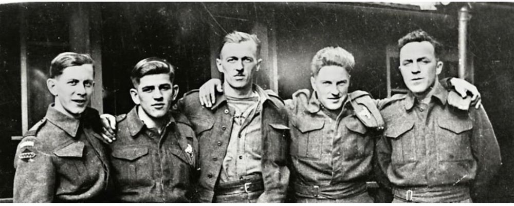 5 men, arms around shoulders in army gear