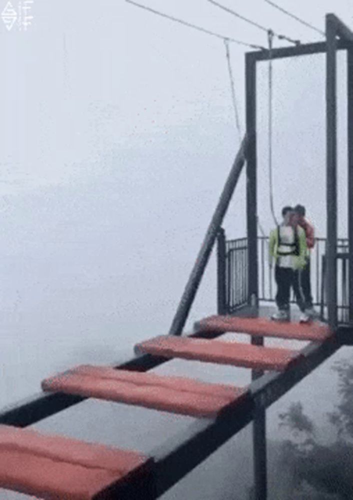 a man and woman are standing on a bridge in the fog .