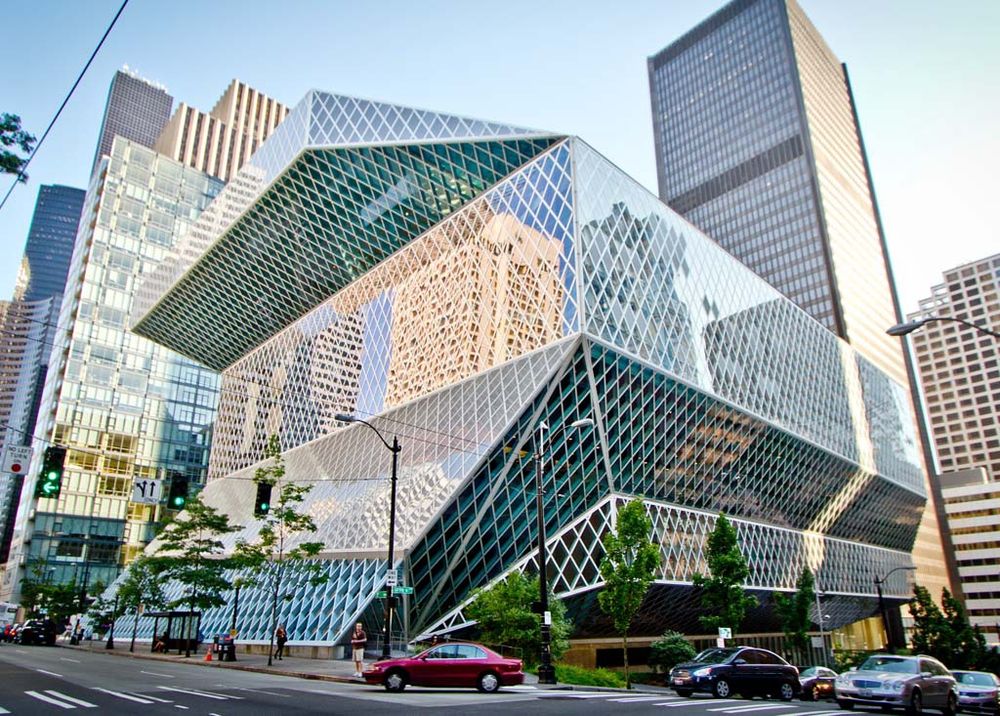 The building is angular, shaped at 45° off the ground on the left and vertical on the right, stepped back from the pavement, with a shaped overhang at the top. Constructed of steel and glass in a cross-mesh design, it reflects its surroundings. This thing is space age!