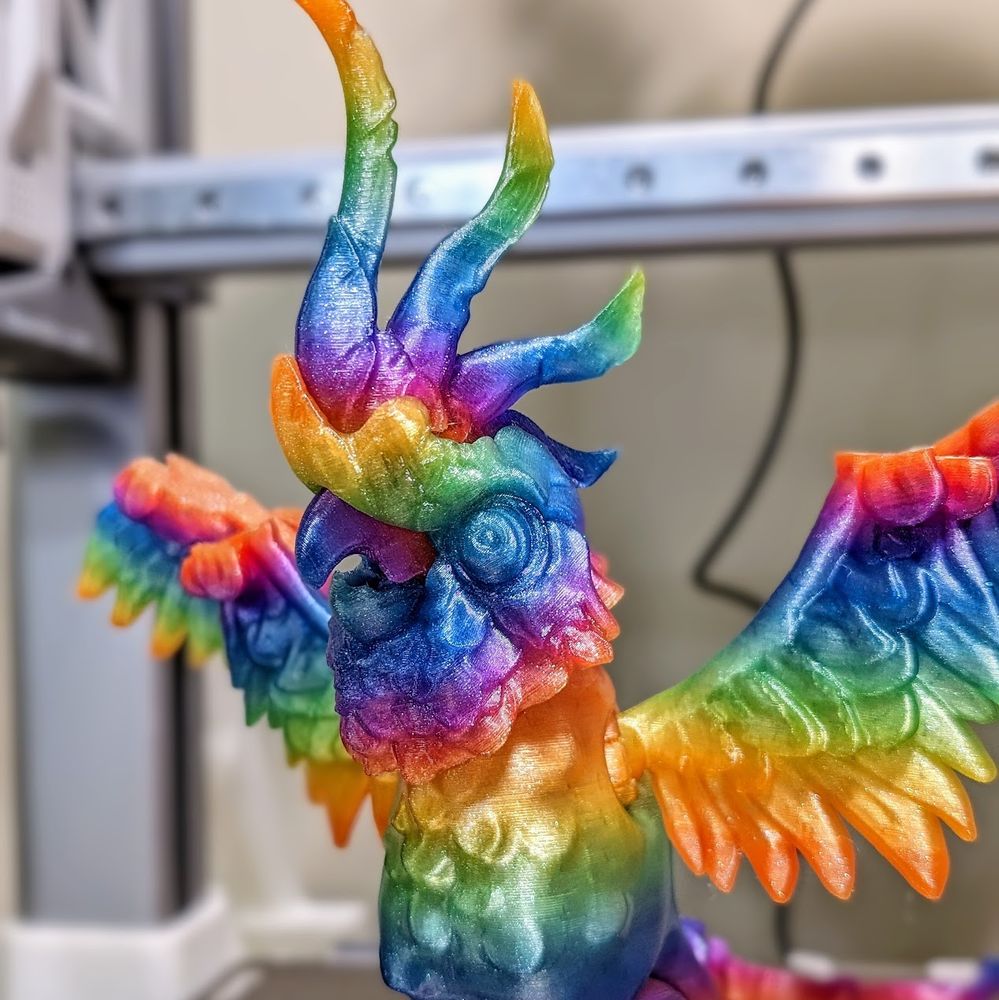 3d printed cockatoo by twisty prints in a glitter rainbow filament standing wings spread on a bambu a1 printer, zoomed in on head