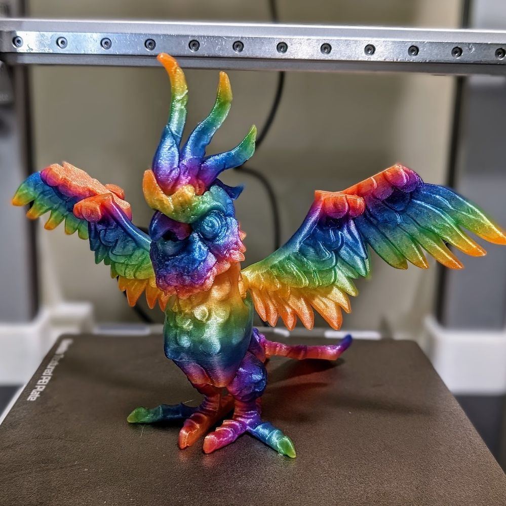 3d printed cockatoo by twisty prints in a glitter rainbow filament standing wings spread on a bambu a1 printer