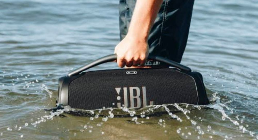 closeup of an arm dragging a JBL speaker against the current in a river