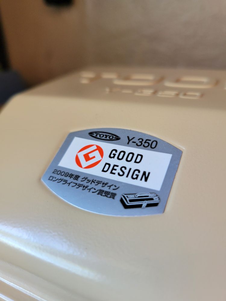 Aluminum badge on a metal box that says good design with a stylized g as  a logo. 