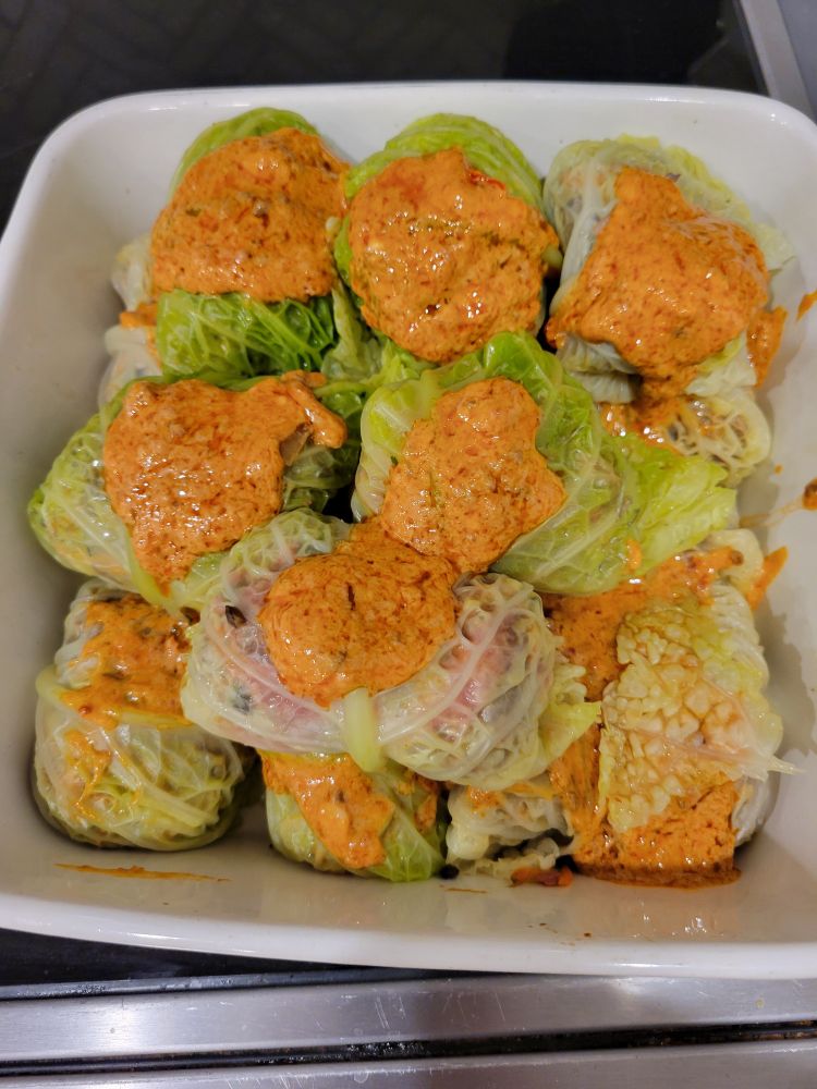 Cabbage rolls topped with an orange sauce. 