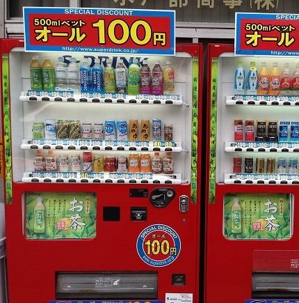 A Japanese soda vending machine that kind of has the same layout as a floppy disk with a big window where the label would be and a small window where the disk cover would be. 