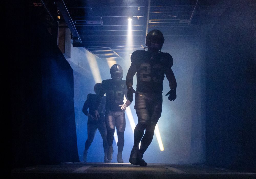 Raiders players run out of the entrance tunnel before the game.