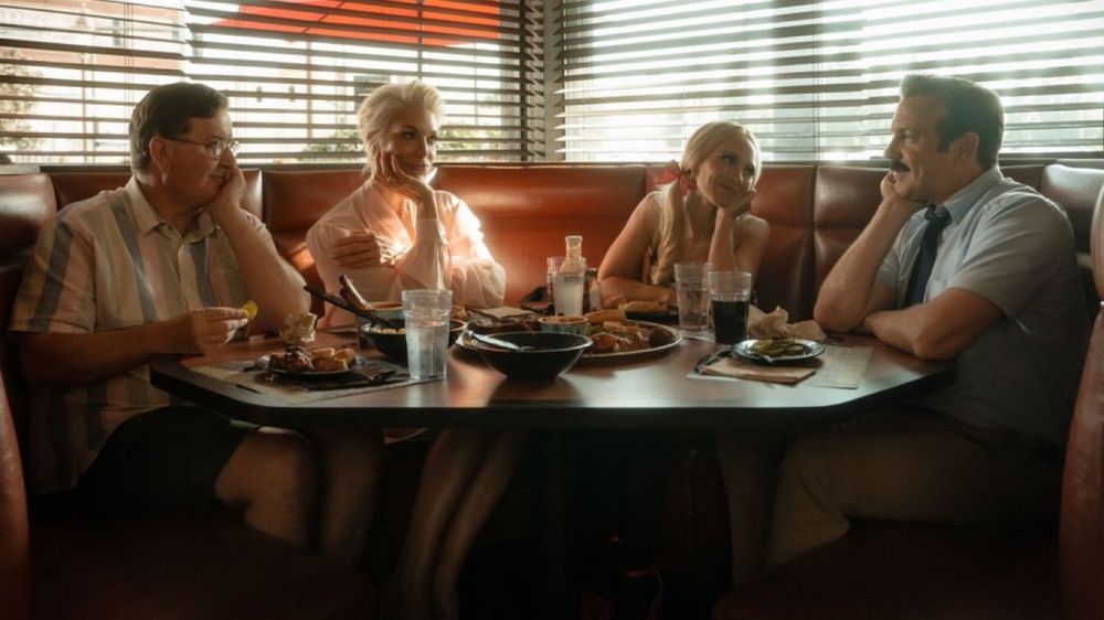 First look still from S4 of ted lasso. Higgins, Becca, Keeley and Ted sat around a table at a BBQ place in Kansas 