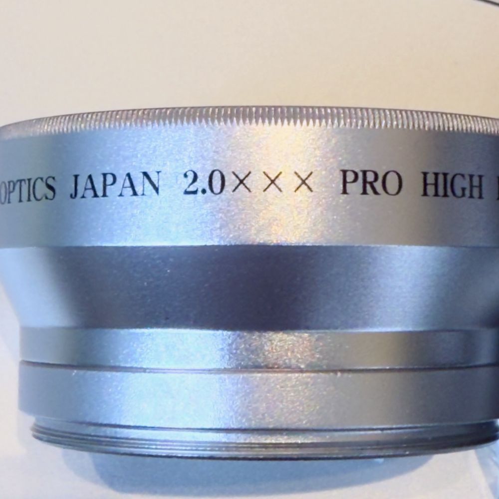 Photo of an auxiliary lens with the text "OPTICS JAPAN 2.0 XXX PRO HIGH [DEFINITION]"