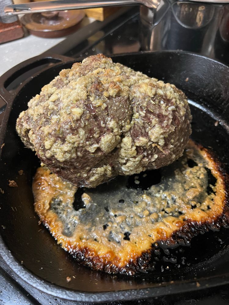 A roasted beast in a cast iron pan with lotsa drippings