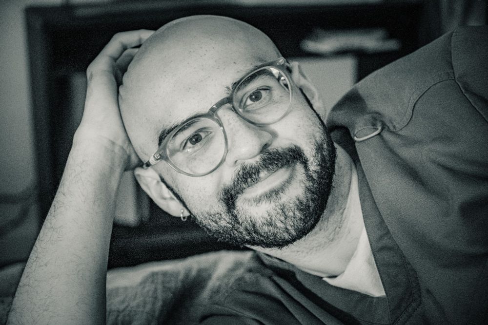 A bald and bearded gentleman in glasses wearing a scrub top