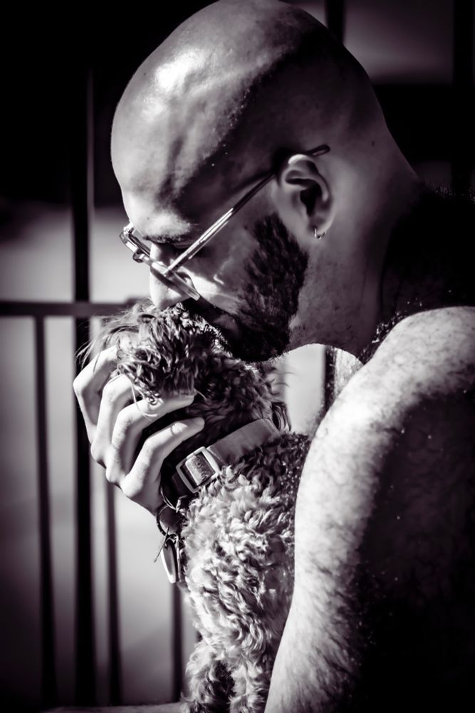 A profile of the same man snuggling my dog porcini on a balcony