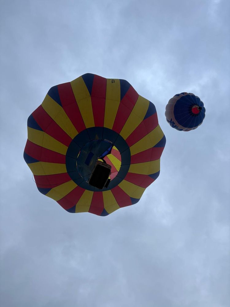 Photo taken from beneath two red-yellow-dark blue hot air balloons.