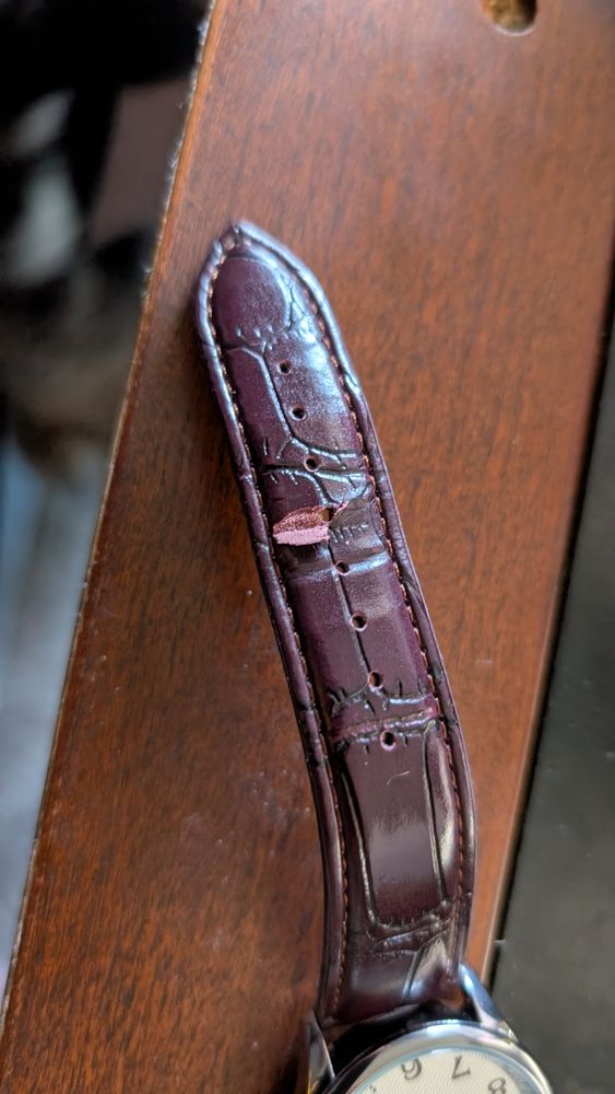 A brown watch strap with a cut/tear in it. 