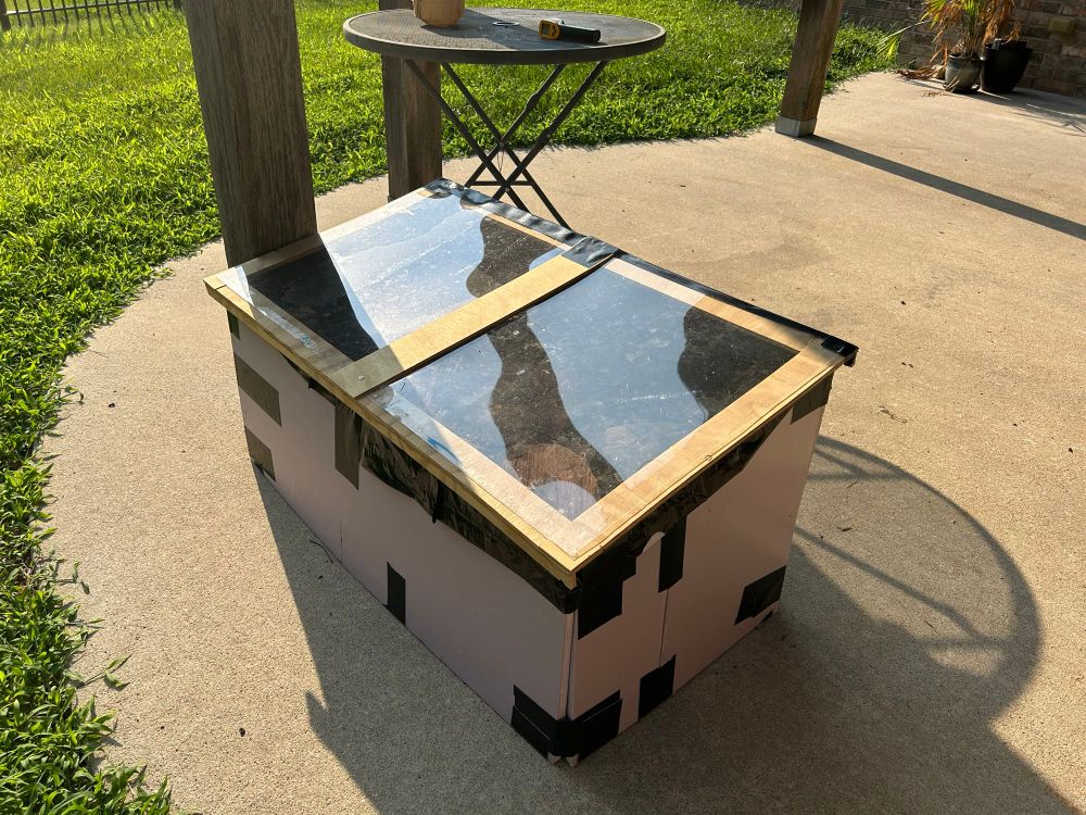 A box made of foam insulation, held together with duck tape, with plexiglass panels on top. It’s in the sun, which made the stuff in it hot. 