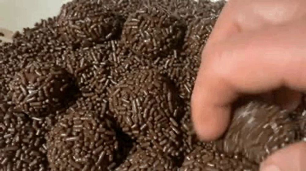 a person is touching a pile of chocolate sprinkles with their fingers .