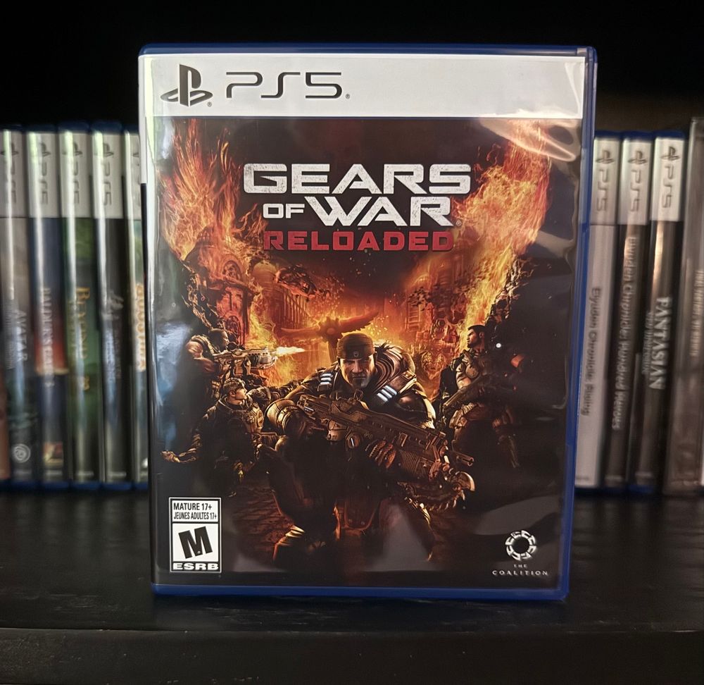 A picture of a physical copy of Gears of War Reloaded for PS5 on a shelf in front of other PS5 games