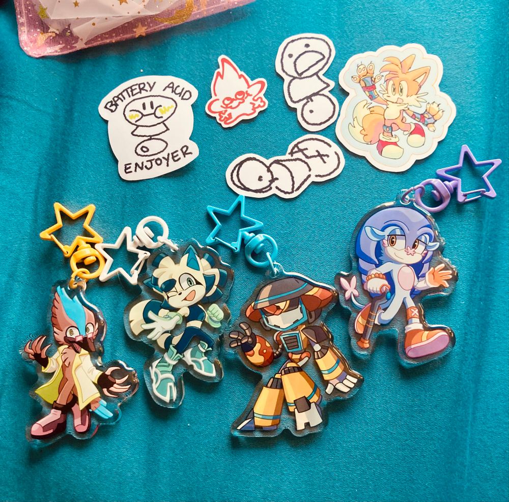 A photo of a series of charms and stickers of Sonic OCs (Team Glue, Professor Kookoo, and MALCoLM).
