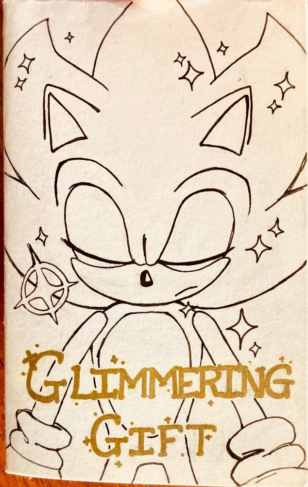 The cover of a folded zine titled Glimmering Gift. It’s a drawing of Super Sonic with his eyes closed. 