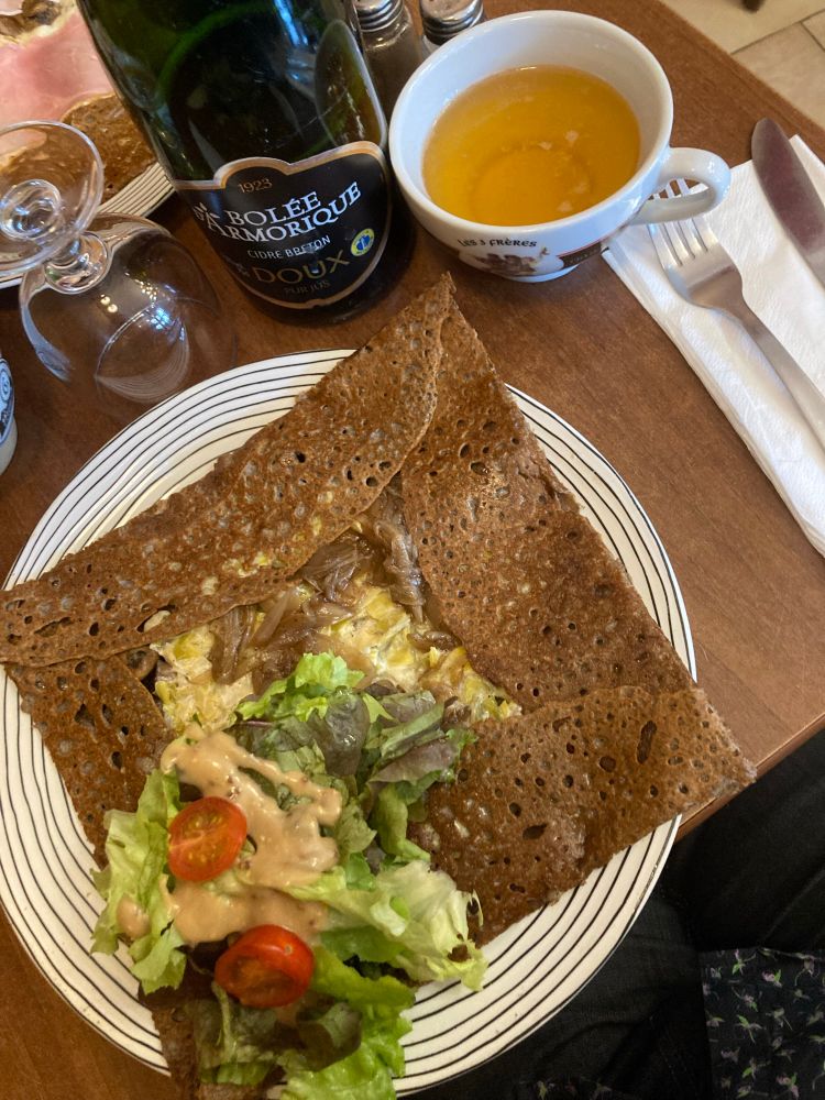 Picture of a galette filled with leeks mushrooms and onions with some salad on the side