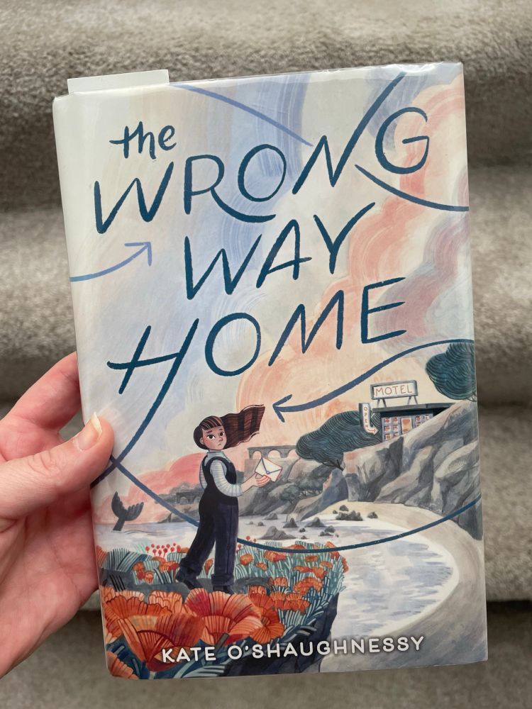 Picture of a hand holding a book called The Wrong Way Home by Kate O’Shaughnessy