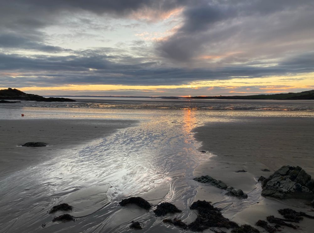 Pale rays of sunshine reflecting on wet sand.