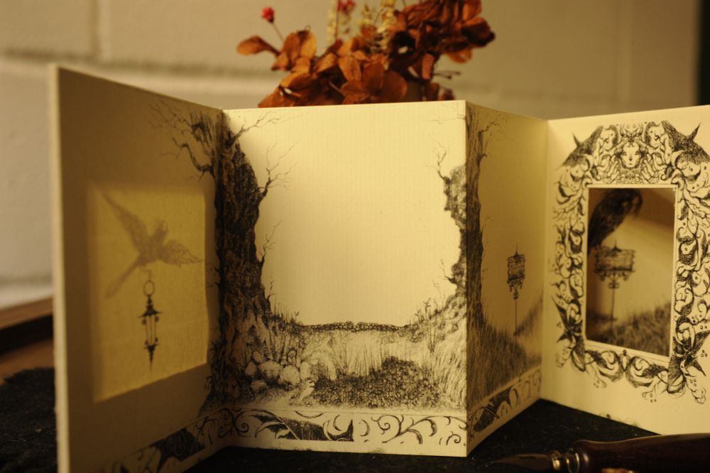 the first half of the zine up until the "mirror". we see an empty field with two trees and a lantern that appears to be floating but, because the light is hitting the zine paper in the correct spot, we see the lantern is not actually floating but being carried by an invisible bird figure (a crow-witch). in the distance we see the mirror reflecting the same field, but places that were supposed to be empty now have more bird-figures