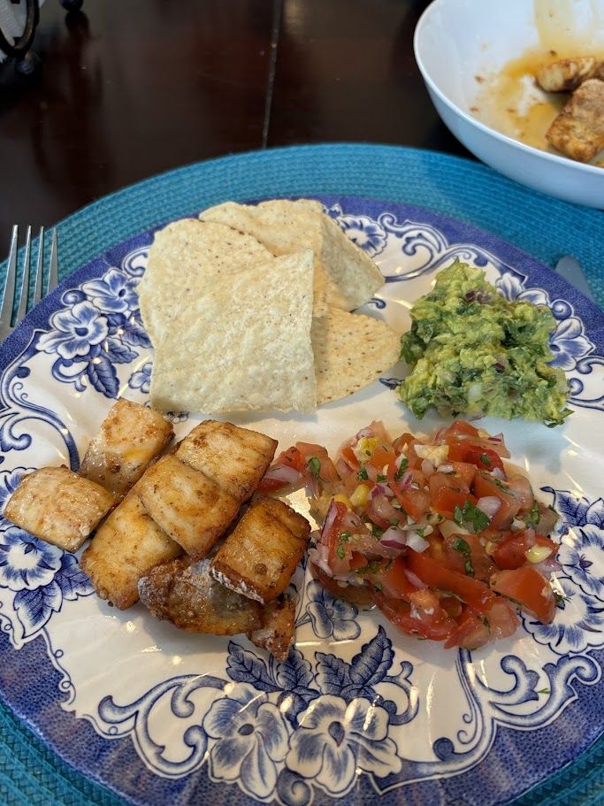 ひとり分お皿に盛った白身魚のスパイス焼き、コーン入りサルサ、ワカモレ、トルティーヤチップス