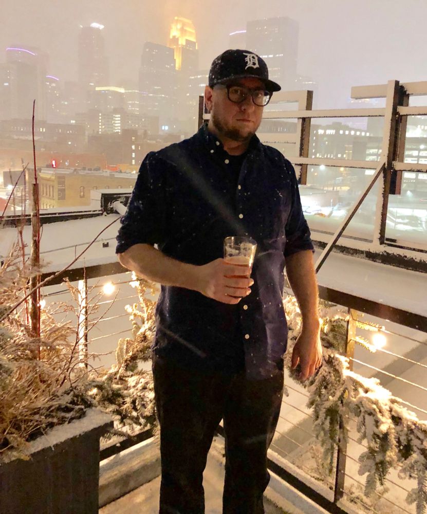 grumpy area man drinks beer on a rooftop during a snowstorm