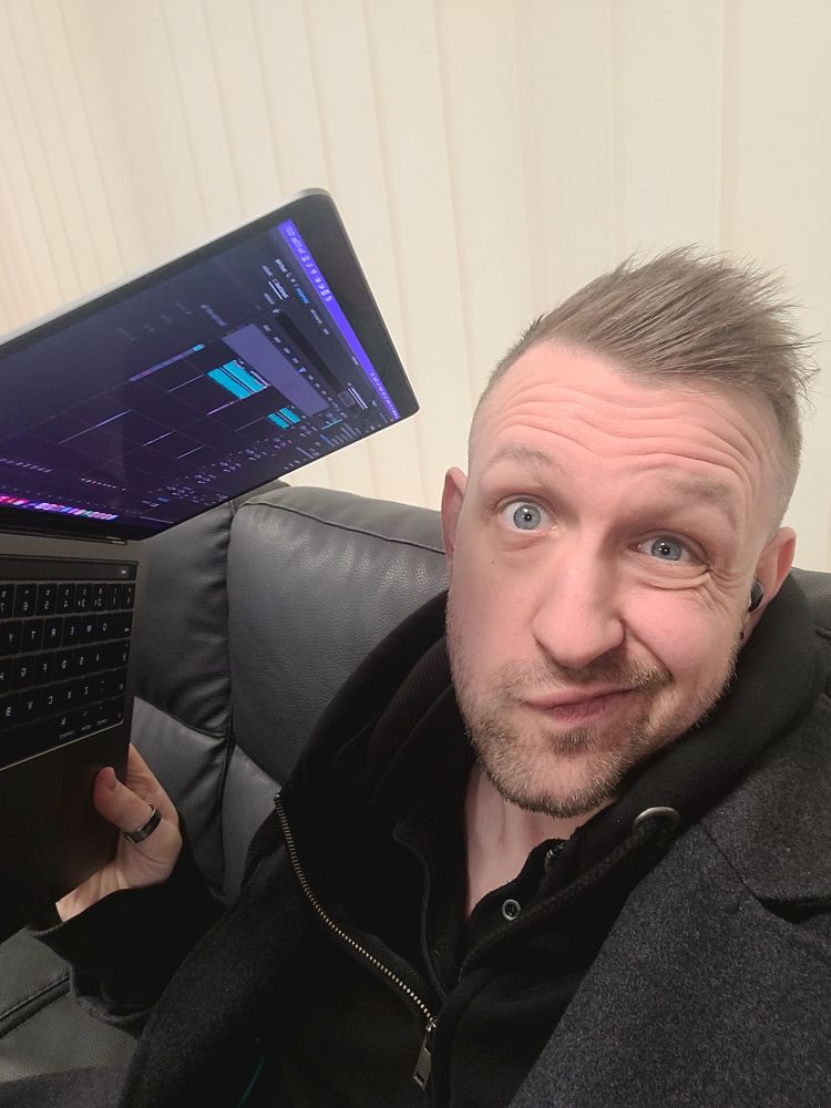 Dungeon Master UK holding a macbook with audio editing software to edit the podcast Roll Britannia