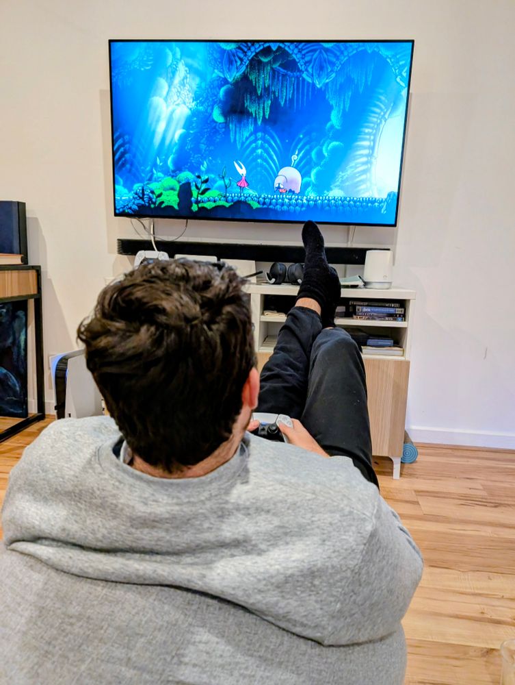 A picture of a man in a beanbag playing Silksong 