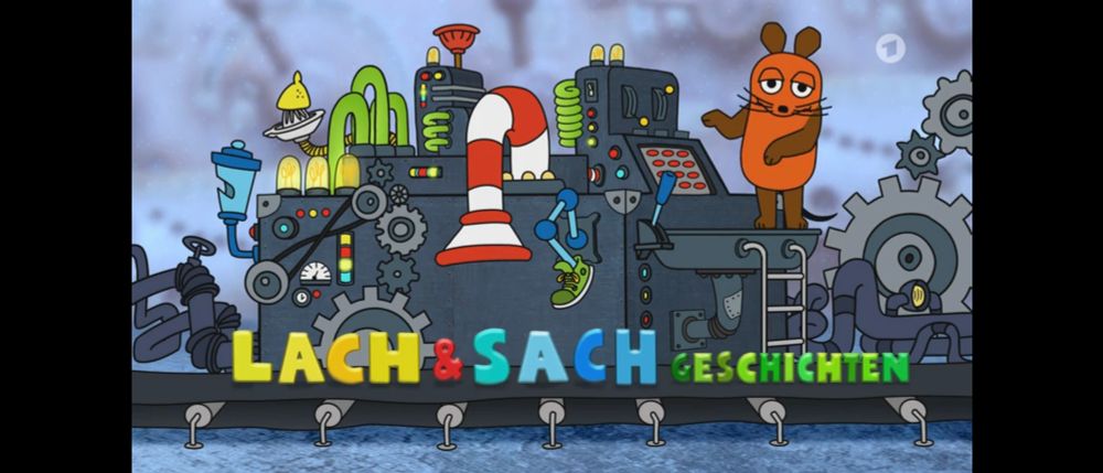 Lach und Sachgeschichten Bild mit der Maus, die auf einer Maschine steht, an der der bunte Text auf einem Fließband vorbeifährt.