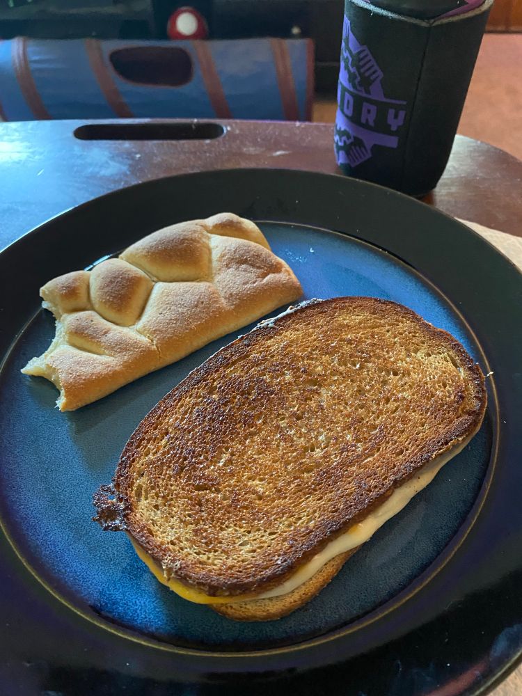 A grilled cheese sandwich next to a pocket pastry with a bite taken out of it.