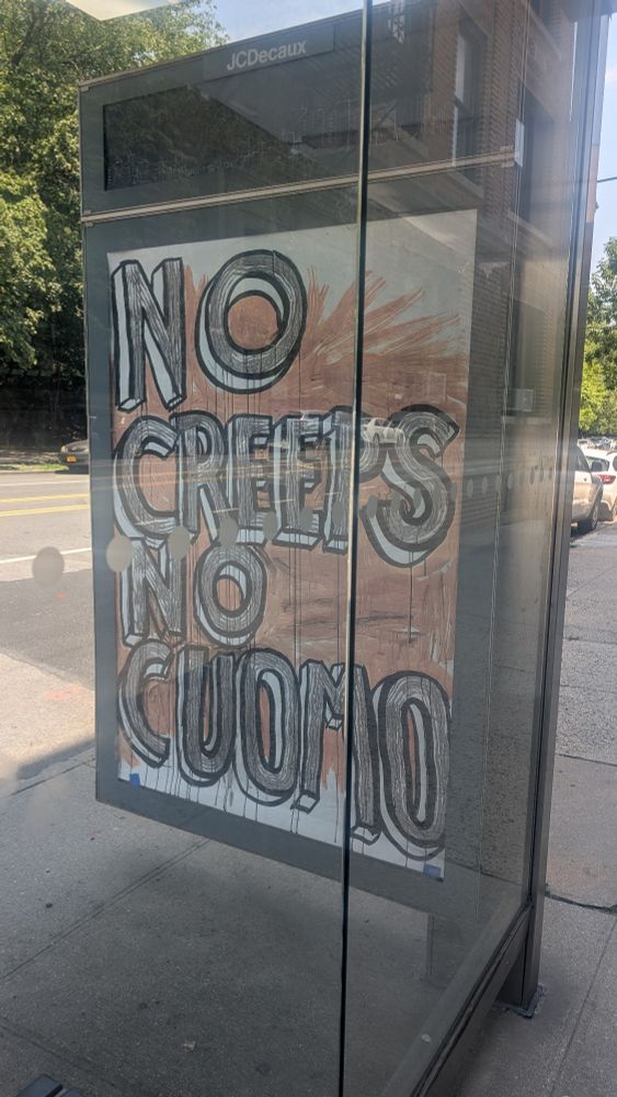 A bus stop in Brooklyn has a large sign in bold letters that says "NO CREEPS NO CUOMO"
