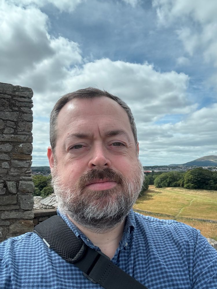 Me, a middle aged white guy, on top of a castle. Edinburgh in the distance. 