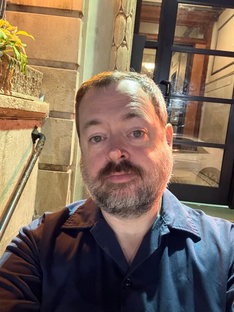 Me, a middle aged white guy with a salt and pepper beard. I’m standing in front of my apartment building.