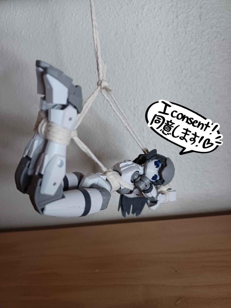 a white and grey acerby model robot is hanging from a hook in rope suspension. a speech bubble reads "I consent!"