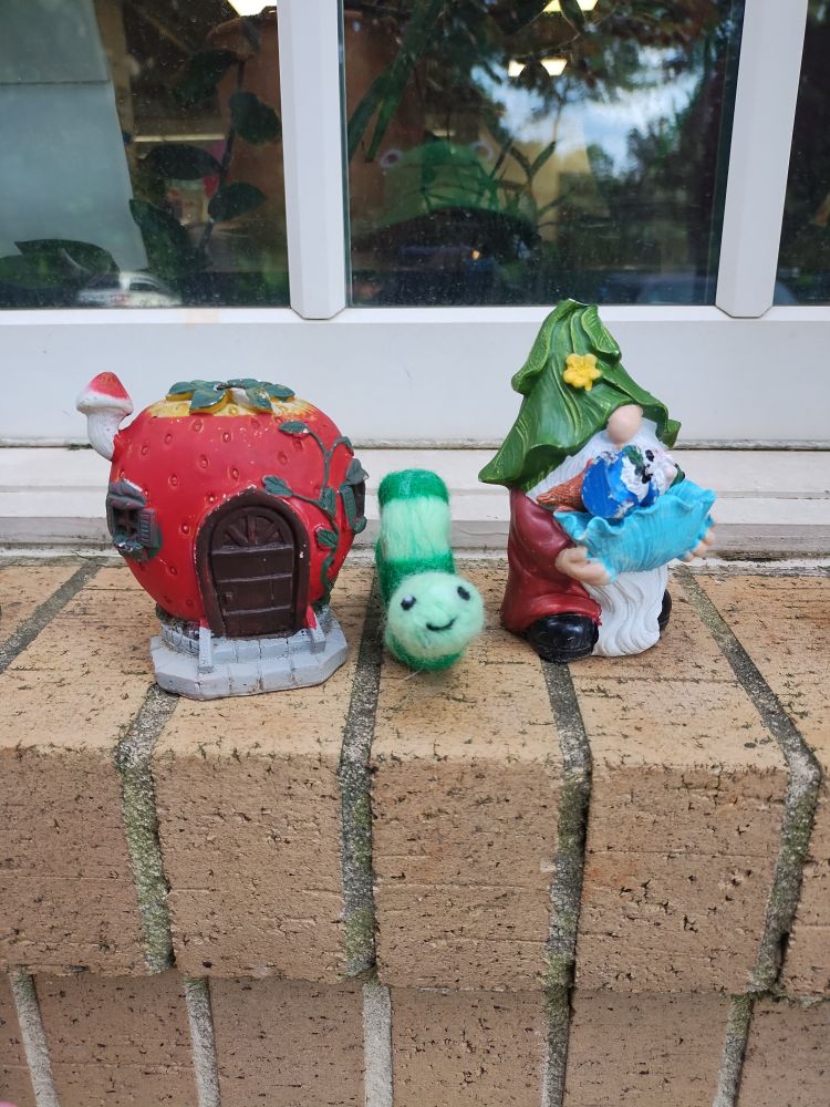 Walter the felt light/dark green worm found some buddies outside on the window ledge, a small apple house and a small gnome 