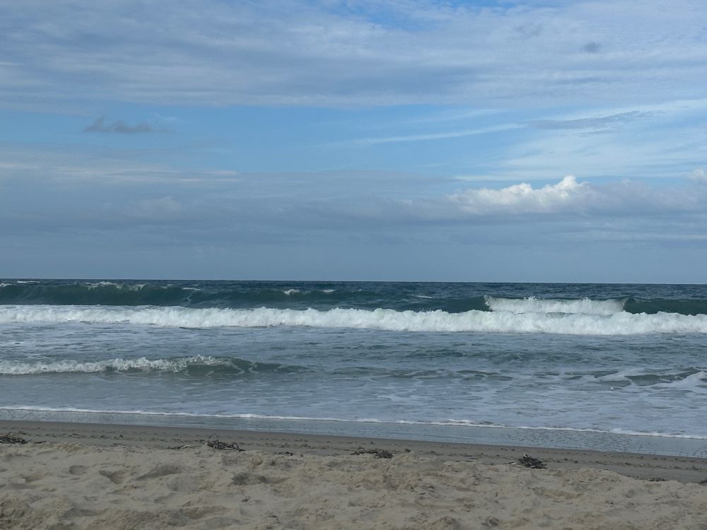 The choppy waters of the Atlantic Ocean on the northern Outer Banks, beneath a sky streaked with greyish clouds.