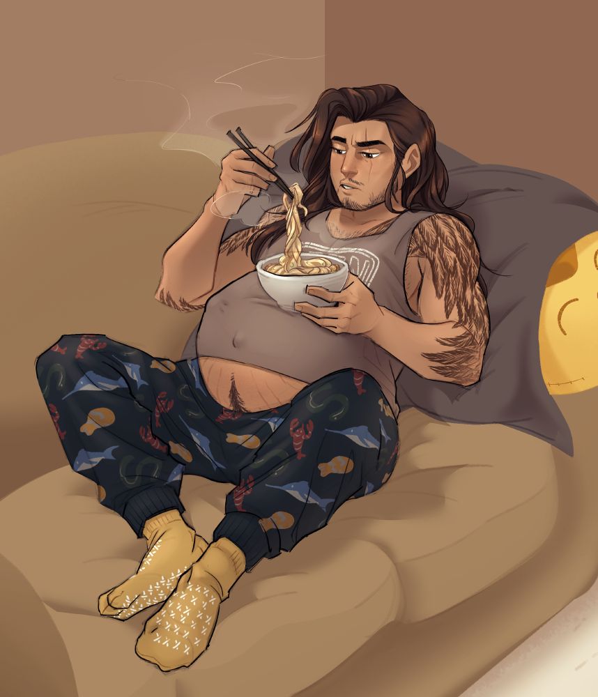 A large, heavily pregnant man leans back on a couch against a large stuffed animal covered in a blanket while he balances a bowl of ramen on top of his belly. His hair is all over, spilling over his shoulder in messy strands. His arms have tattooed feathers that resemble bird wings. He wears a pair of sleep pants that have marine animals printed on them, and yellow socks with white grips. From under a tightly stretched shirt, a strip of skin peeks through to reveal his belly with stretchmarks and a happy trail following down from his navel to his groin.